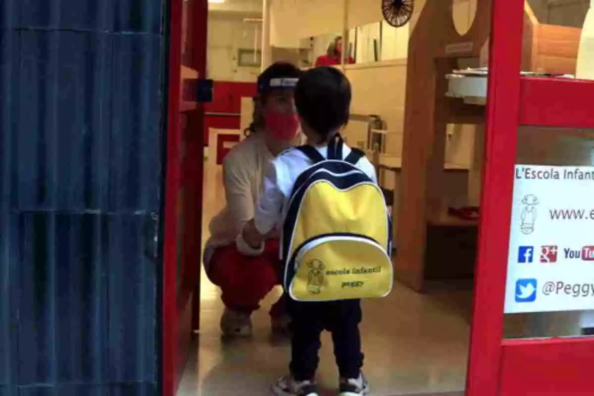 A kid at school being welcomed by a teacher with a face mask