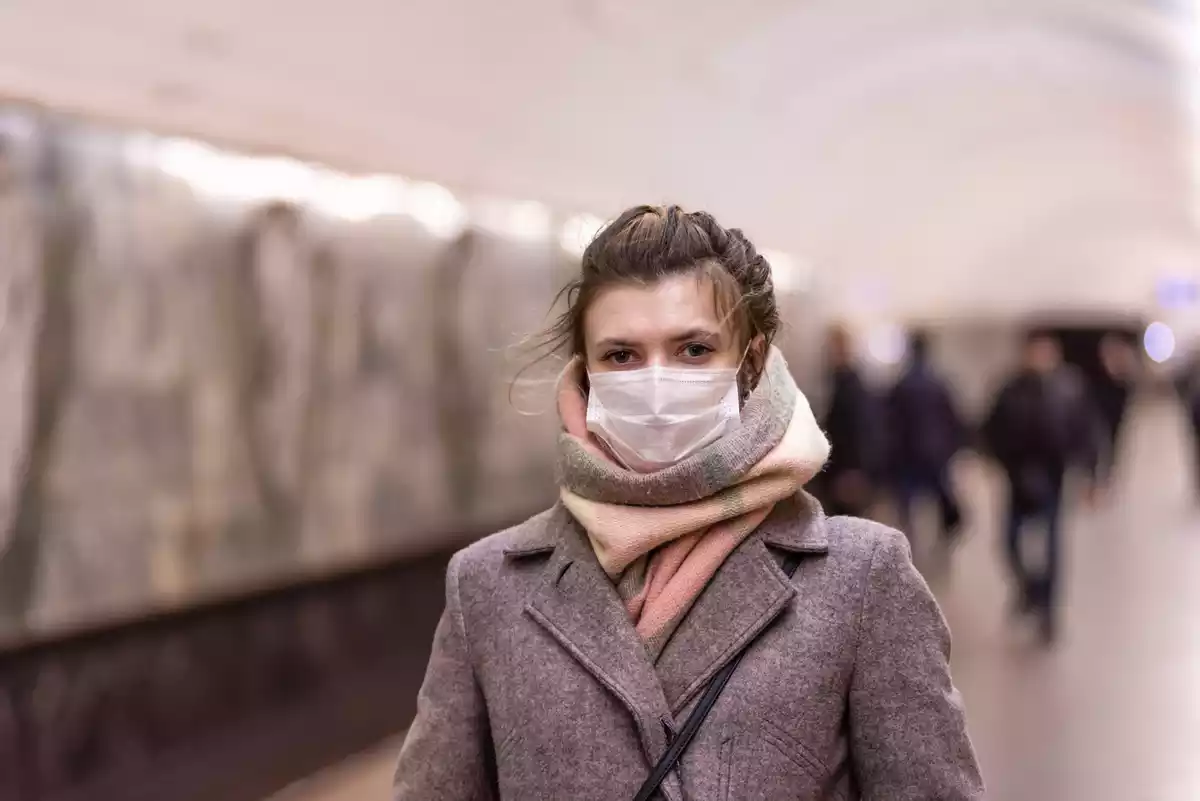A woman in the underground wearing a mask