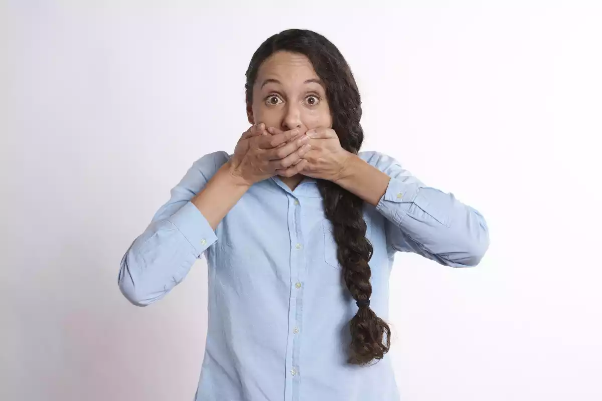A woman hiding his laughing mouth with his hands