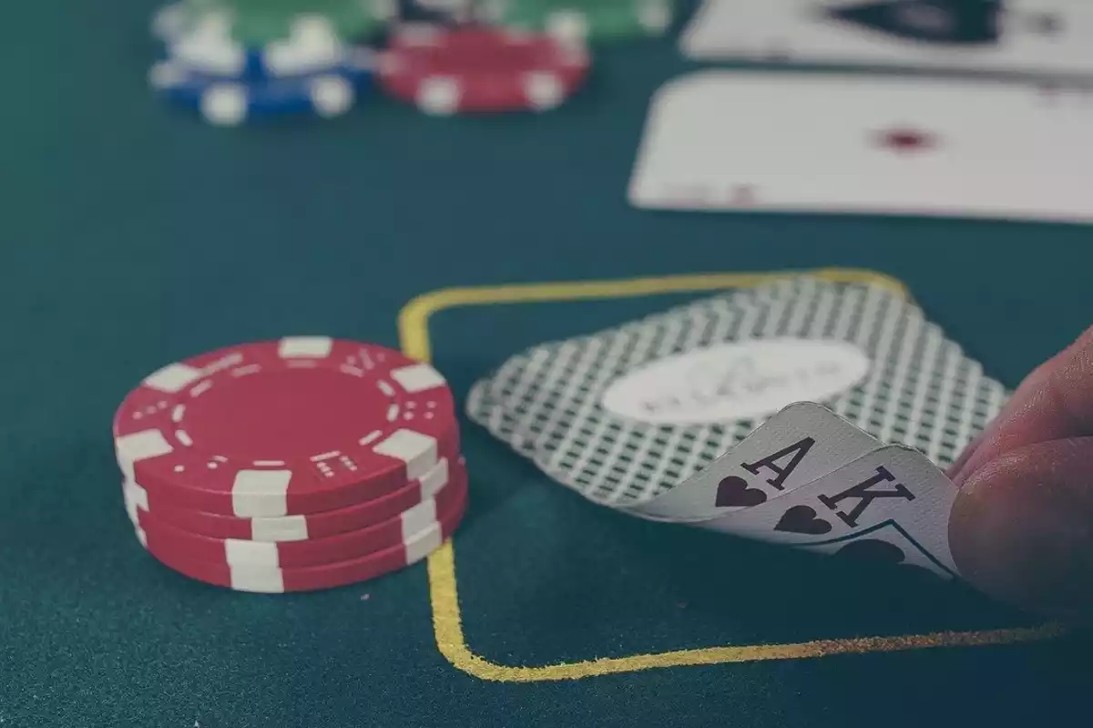 Una mesa de juego con cartas y fichas de póker y un hombre levantando una carta